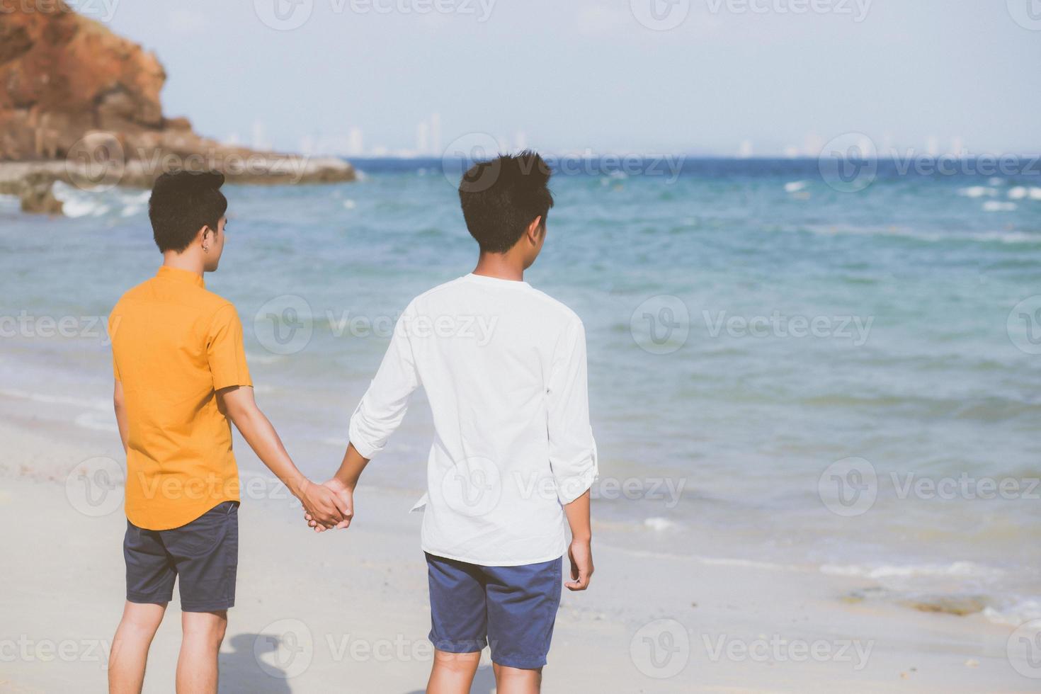 omosessuale giovane coppia asiatica in piedi insieme sulla spiaggia in estate, asia gay che si tiene per mano andando in mare per il tempo libero e rilassarsi con romantico e felice in vacanza al mare, lgbt con concetto legale. foto