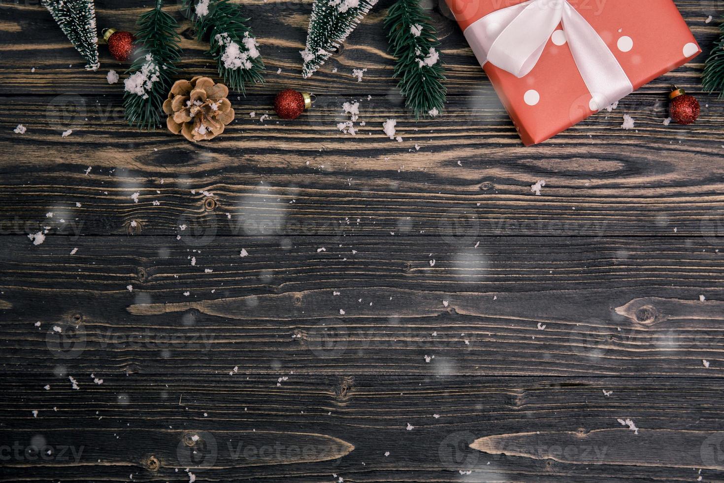 composizione per le vacanze di natale con decorazione di scatola regalo rossa su sfondo di legno, capodanno e natale o anniversario con regali su tavola di legno in stagione, vista dall'alto o distesa. foto