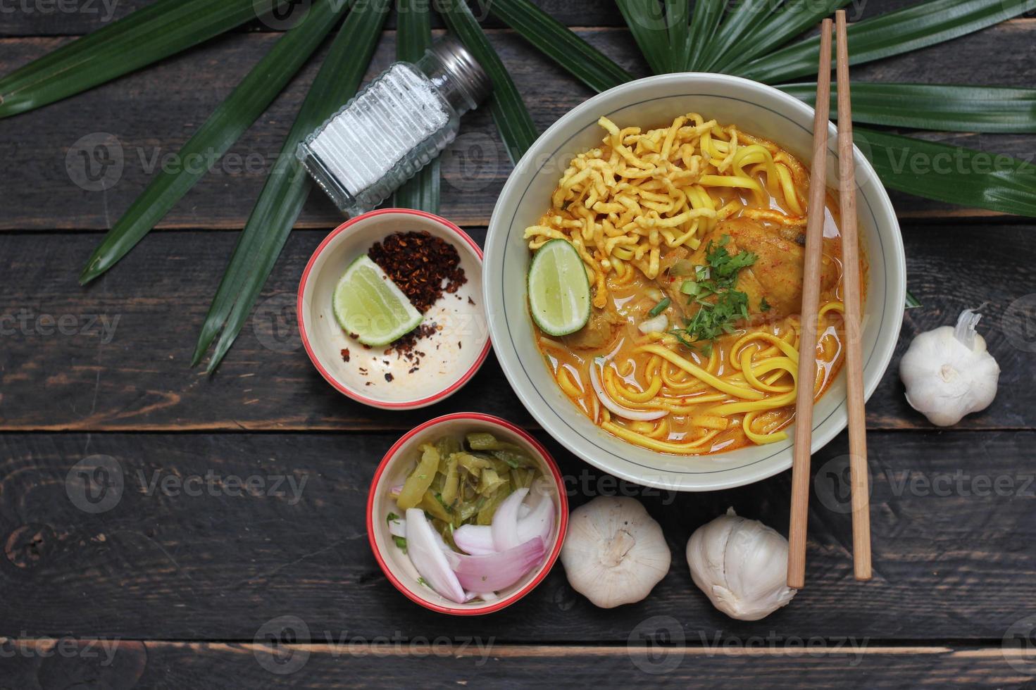 ricetta khao soi, khao soi, khao soi kai, thai noodles khao soi, pollo al curry con condimento servito su tavola di legno foto