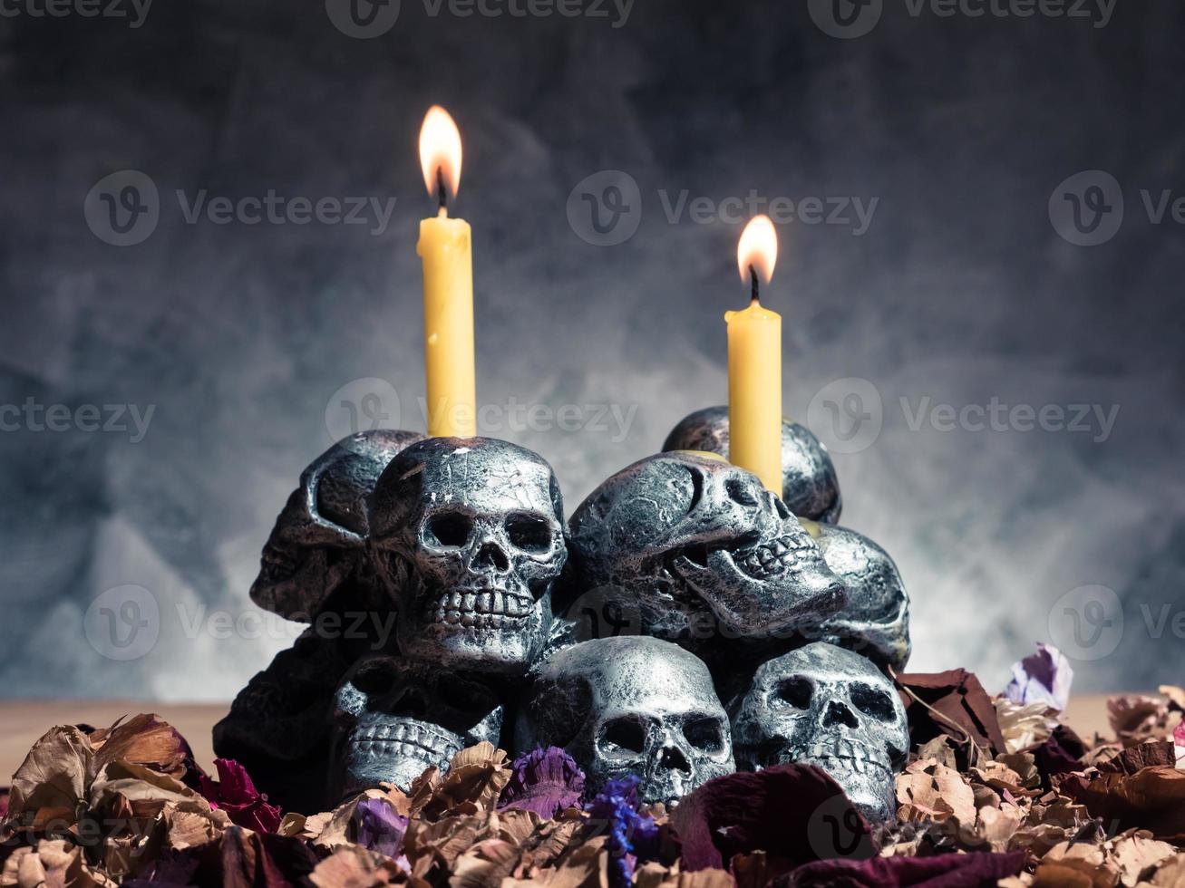 teschi con candele accese e fiori secchi su sfondo scuro. foto