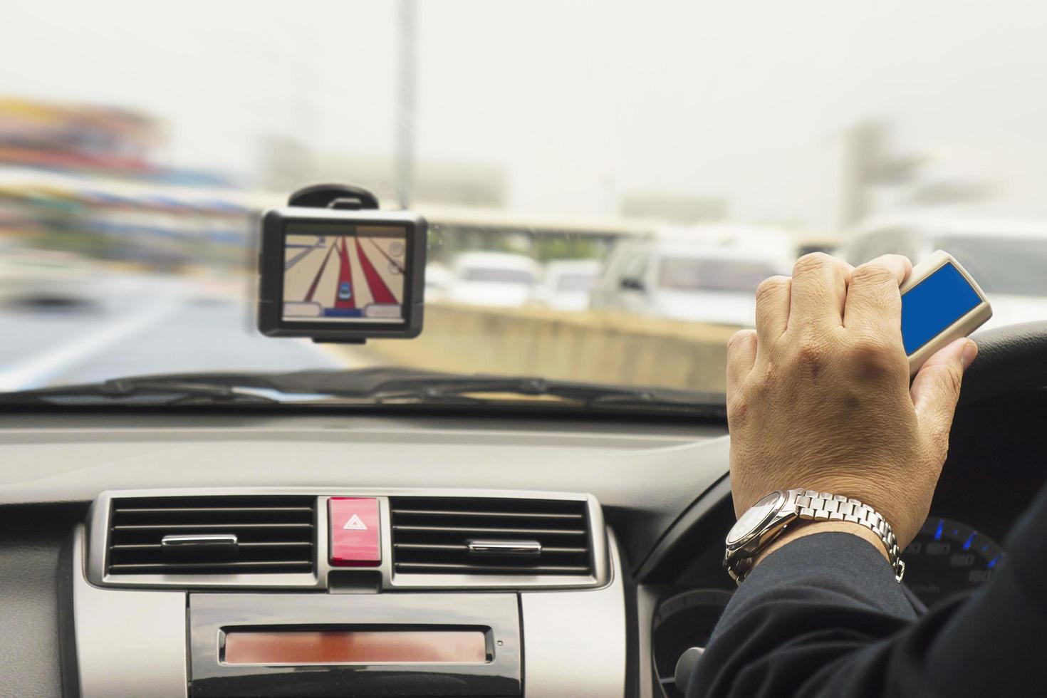 uomo che guida l'auto utilizzando il navigatore e tenendo il dispositivo elettronico del sistema di riscossione dei pedaggi foto