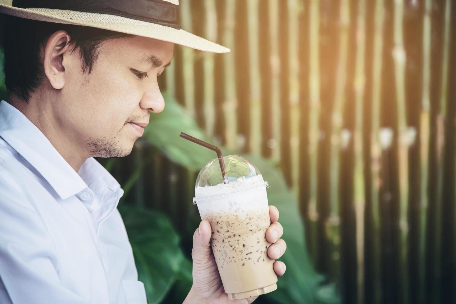 l'uomo asiatico casual beve il caffè ghiacciato felicemente in natura - le persone con il caffè nel concetto di natura foto