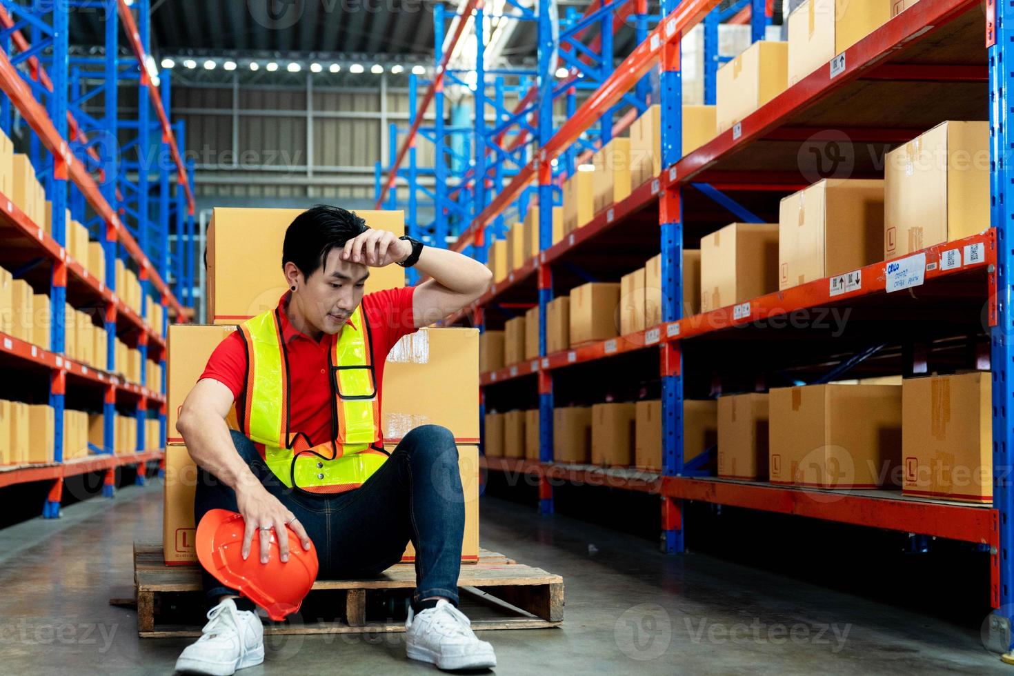 stress stanco asiatico lavoratore maschio lavoro duro lavoro affaticamento seduto a riposo nell'industria dell'inventario del carico di magazzino. foto