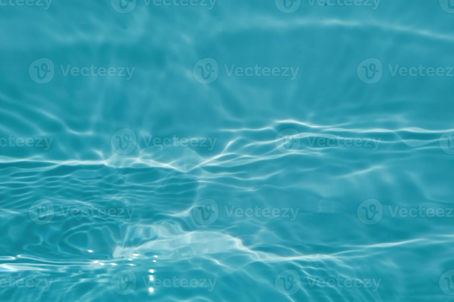 sfocatura sfocata trasparente di colore blu chiaro acqua calma superficie texture con schizzi e bolle. sfondo di natura astratta alla moda. onda d'acqua alla luce del sole con spazio di copia. struttura ad acquerello blu foto