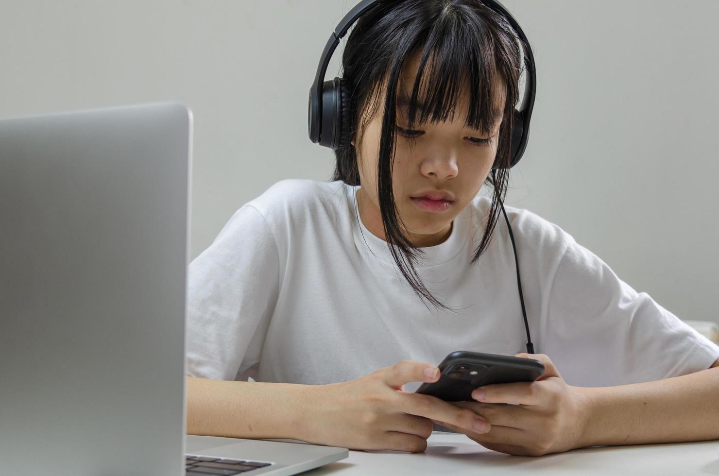 ragazza che indossa le cuffie che studia online con un computer portatile e ascolta musica rilassante o riproduce i social media su Internet a casa. foto