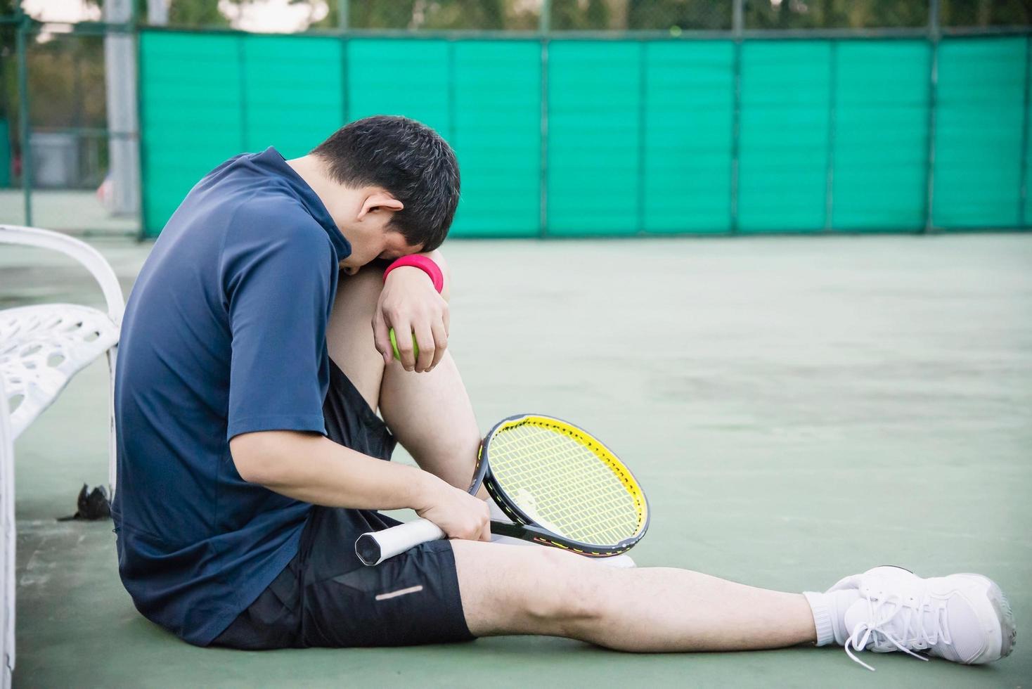 giocatore di tennis triste seduto in tribunale dopo aver perso una partita - persone nel concetto di gioco di tennis sportivo foto