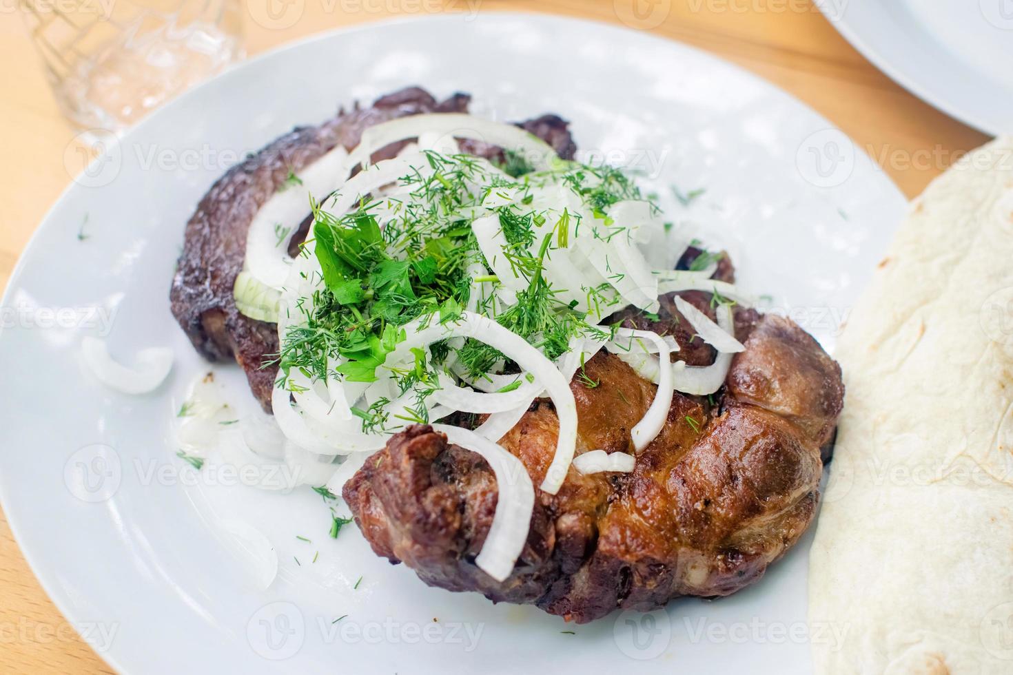 appetitosa braciola di maiale alla griglia con cipolle e aneto sul piatto bianco. carne succosa. foto