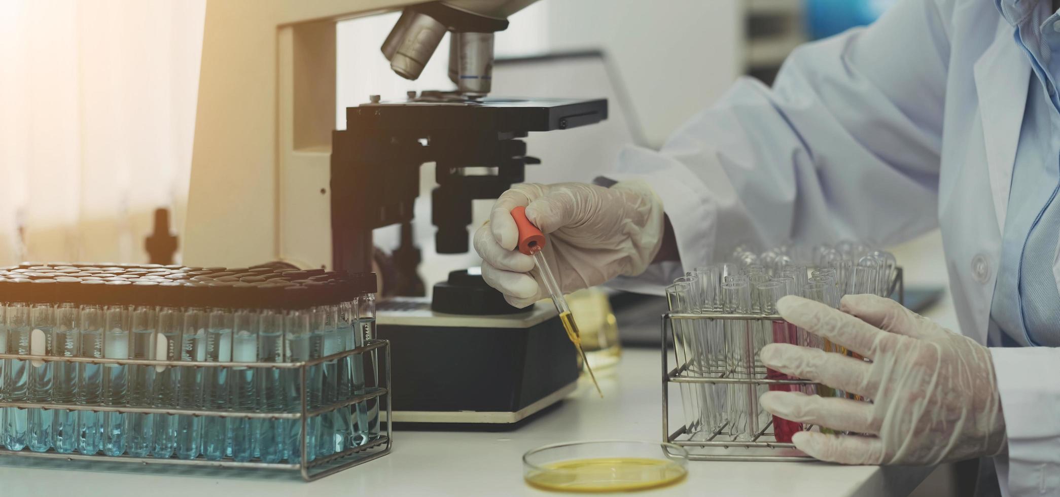 ricerca di laboratorio di biochimica in primo piano, il chimico sta analizzando il campione in laboratorio con apparecchiature per microscopio ed esperimenti scientifici vetreria contenente liquido chimico. foto