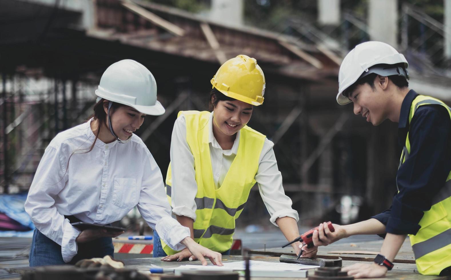 tre esperti ispezionano cantieri di edifici commerciali, progetti immobiliari di edifici industriali con ingegneri civili, gli investitori utilizzano laptop in background a casa, intelaiatura di casseforme in cemento. foto