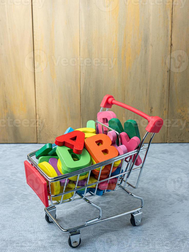 l'alfabeto multicolore nel carrello per l'istruzione o il concetto di marketing foto