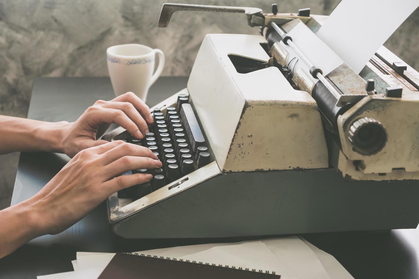 primo piano delle mani maschili che digitano sulla macchina da scrivere sulla scrivania. tono vintage foto