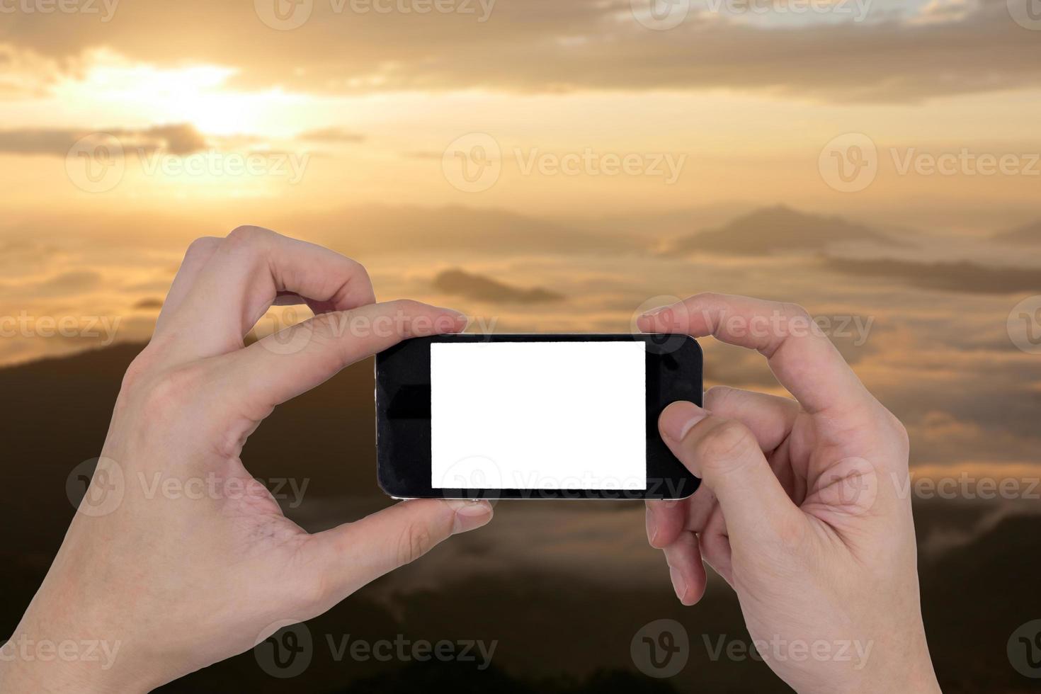 mani maschili che tengono un telefono cellulare con schermo bianco vuoto touch su sfondo sfocato paesaggio naturale. foto