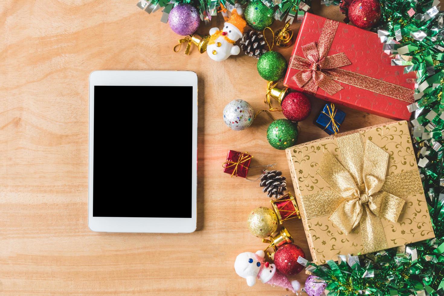 vista dall'alto di scatole regalo con decorazioni natalizie e tablet su sfondo tavolo in legno foto
