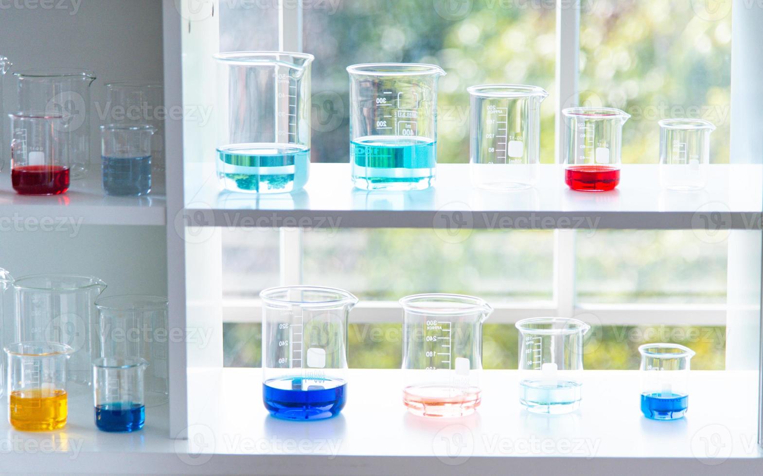 preparazione di attrezzature di laboratorio come vetreria, tubo con blu e liquido sul tavolo bianco. l'esperimento di chimica nella ricerca scientifica foto