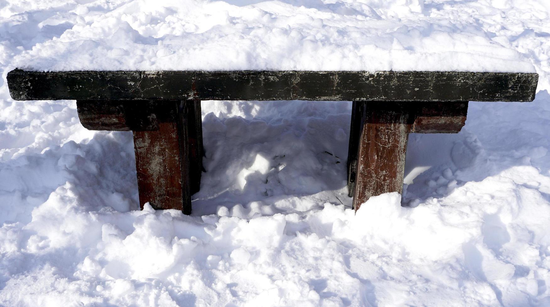 neve e panca di legno nell'inverno della foresta della passerella foto