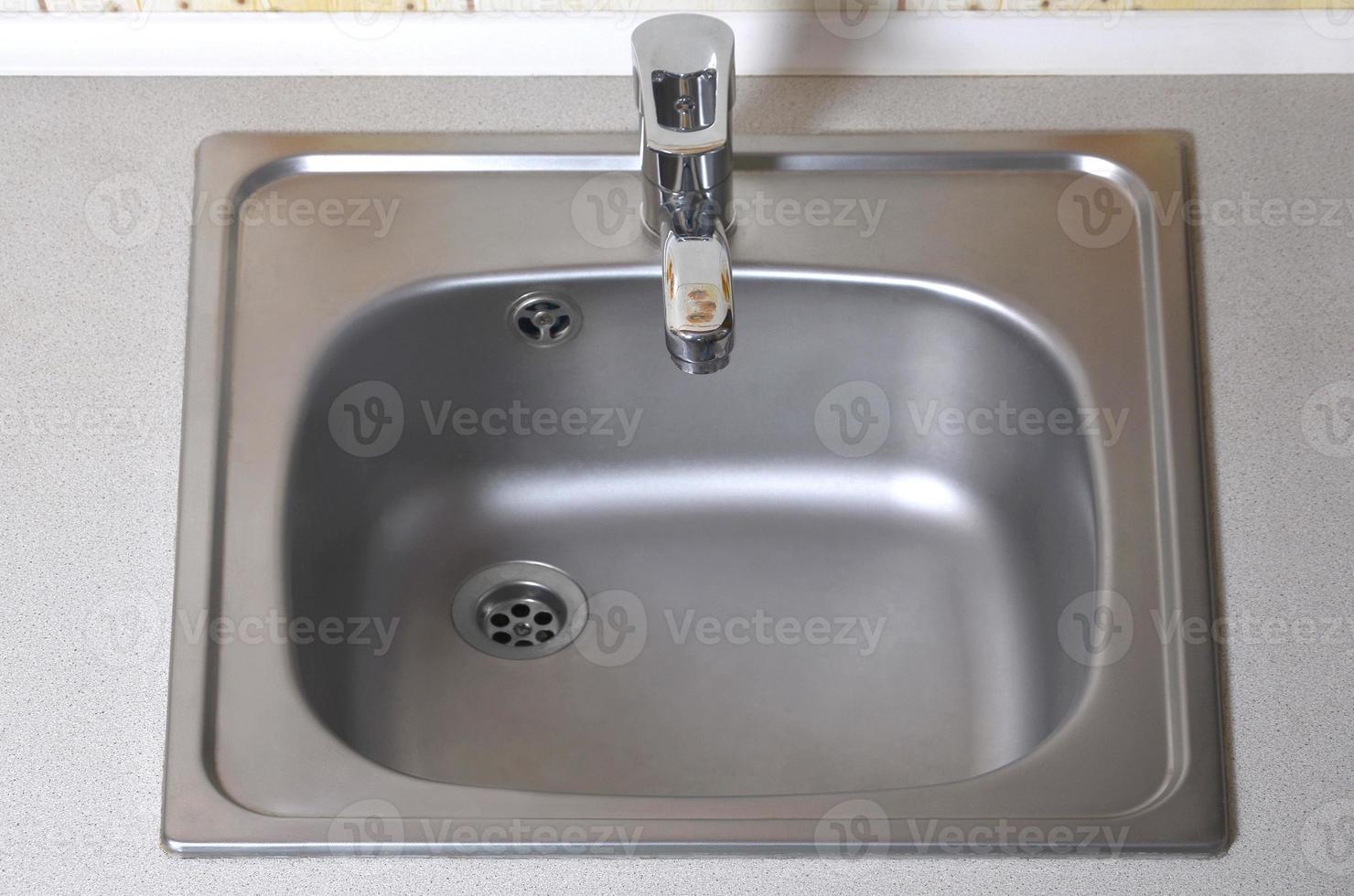 lavabo con rubinetto in argento. nuova attrezzatura nel bancone della cucina foto