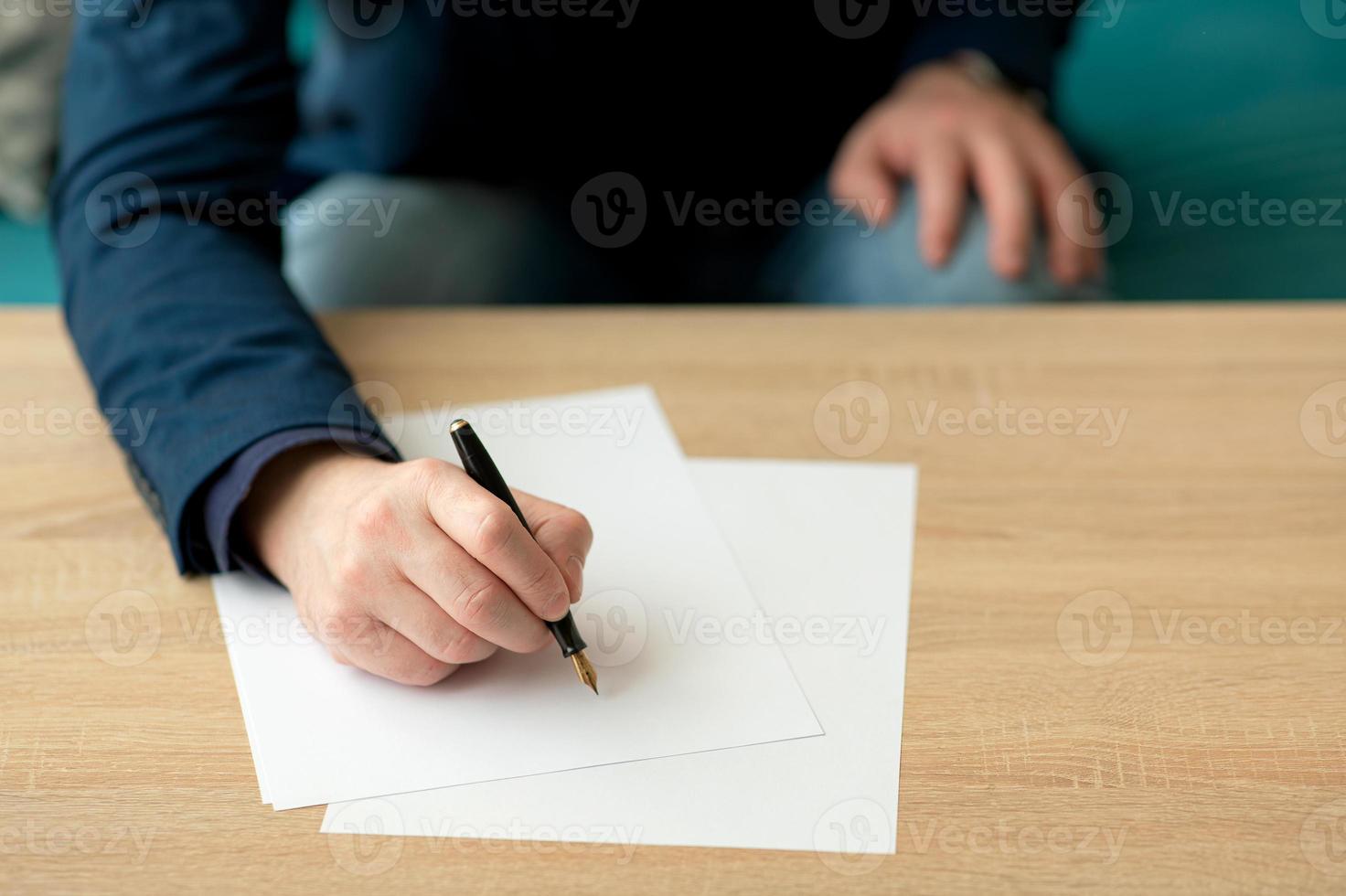 uomo d'affari in ufficio scrive una lettera o firma un documento su un pezzo di carta bianca con una penna stilografica con pennino. primo piano delle mani di un uomo d'affari in un vestito foto