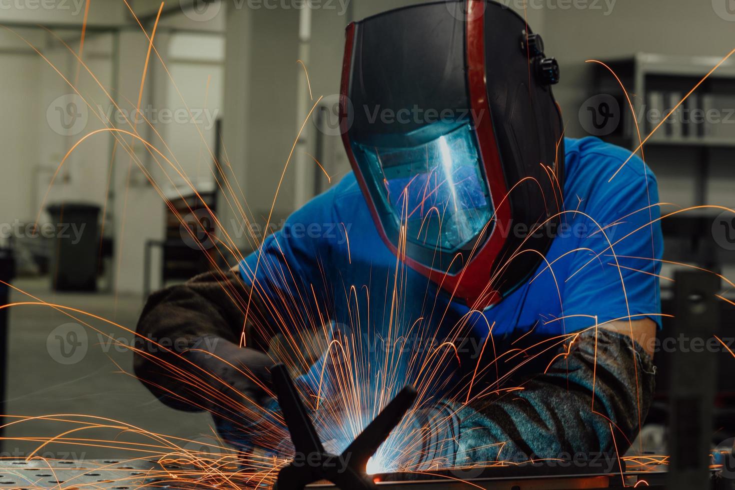 saldatore professionista dell'industria pesante che lavora all'interno della fabbrica, indossa il casco e inizia a saldare. messa a fuoco selettiva foto