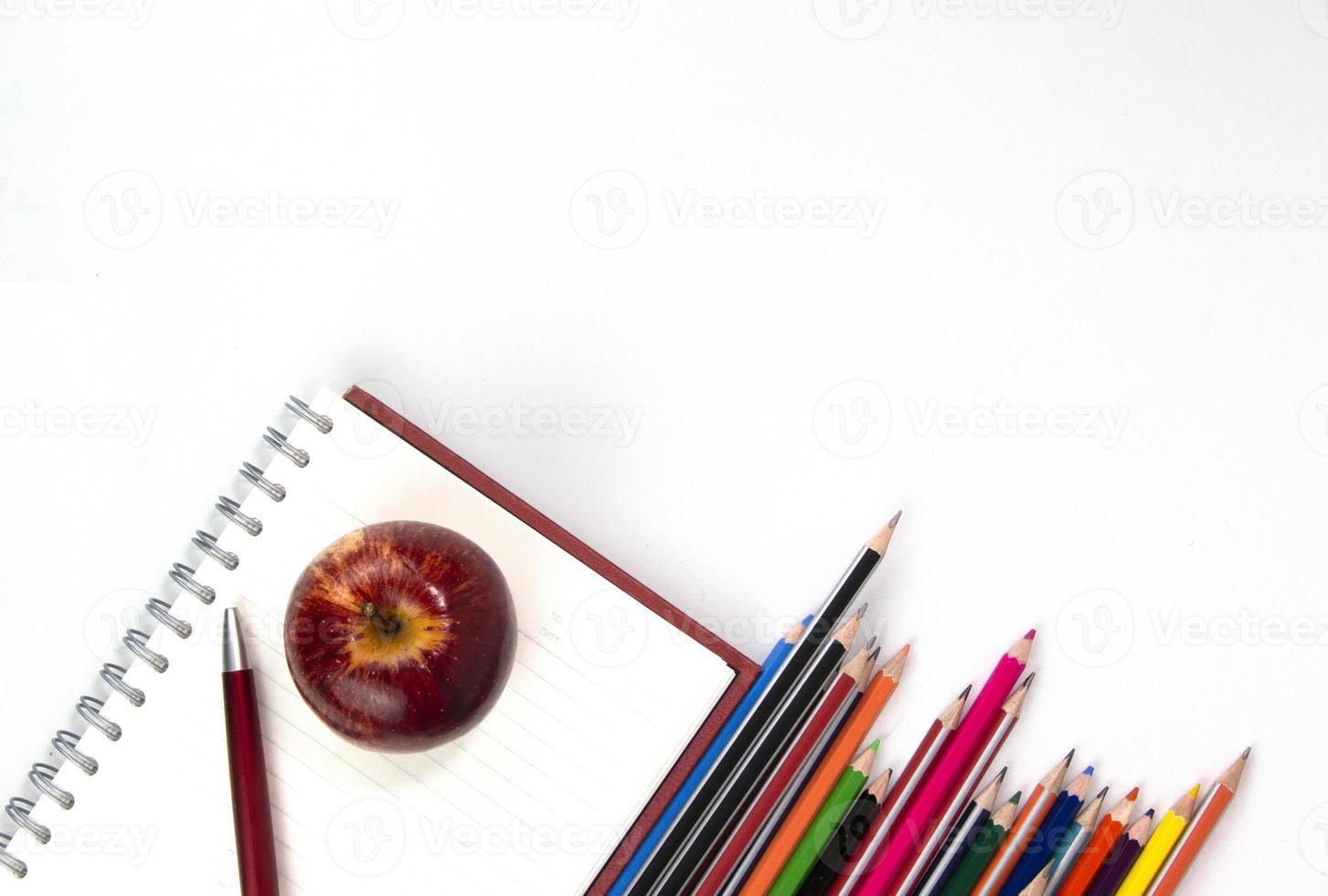 concetto di ritorno a scuola con materiali didattici, taccuino, mela, penna isolati su sfondo bianco. modello di concetti vista dall'alto foto