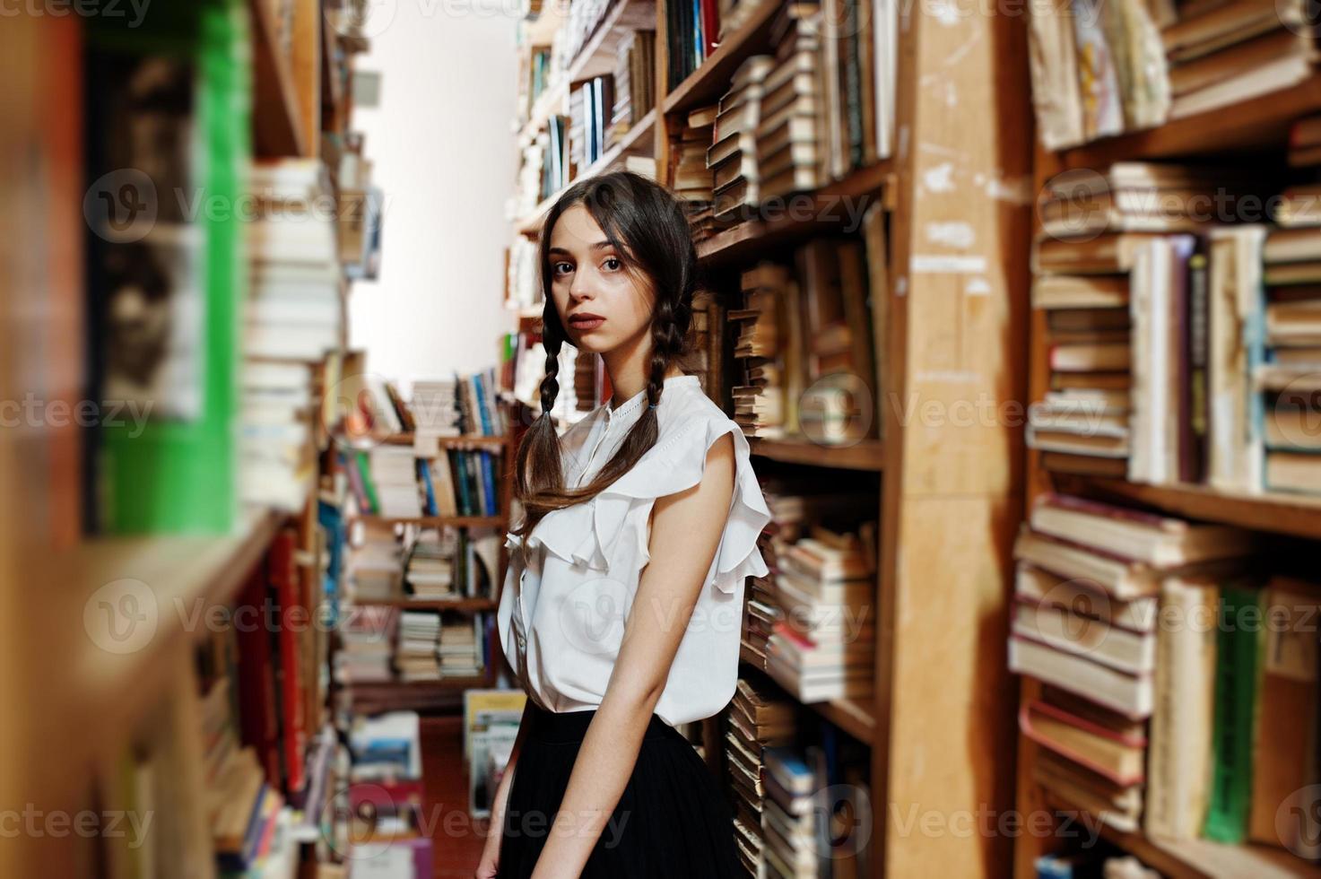 ragazza con le trecce in camicetta bianca alla vecchia biblioteca. foto