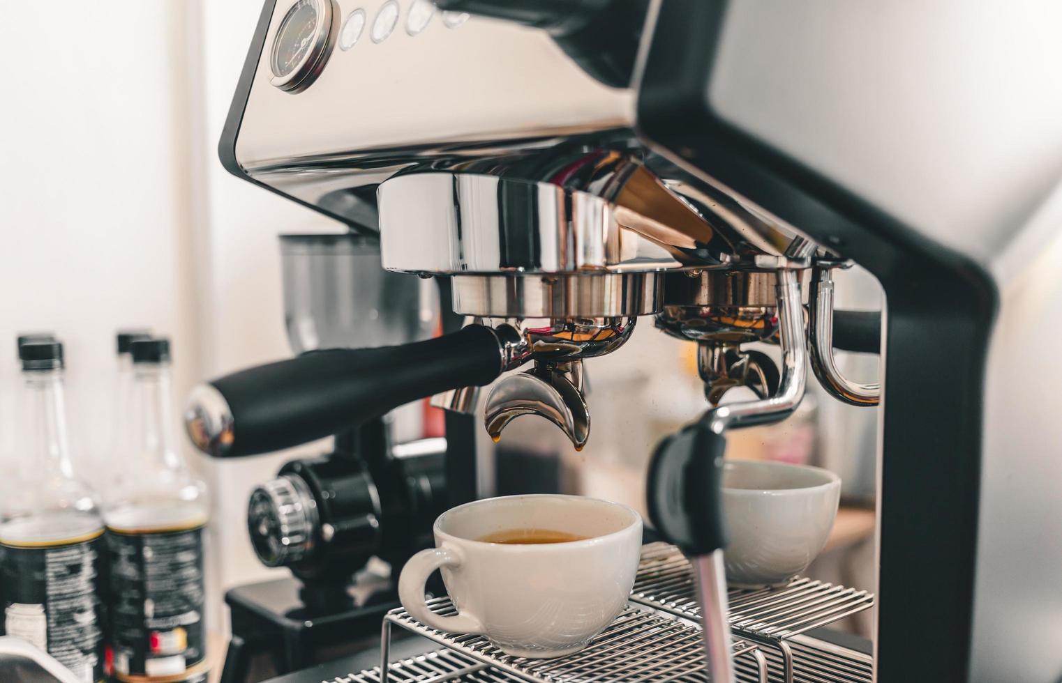 estrazione del caffè dalla macchina da caffè professionale barista.espresso che versa da una macchina da caffè in una tazza di caffè in una caffetteria. foto