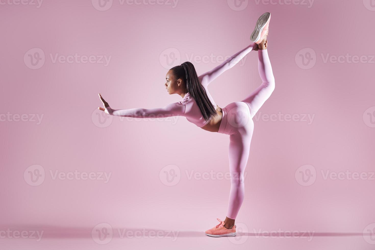 bella giovane donna in abbigliamento sportivo facendo esercizi di stretching su sfondo rosa foto