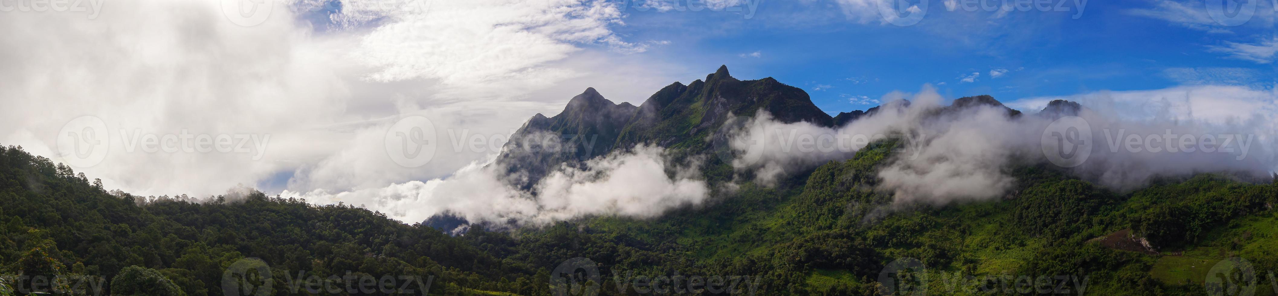 panoramico. paesaggio di montagna verde c'è una nebbia nelle montagne. il cielo è azzurro e le nuvole sono bianche. foto