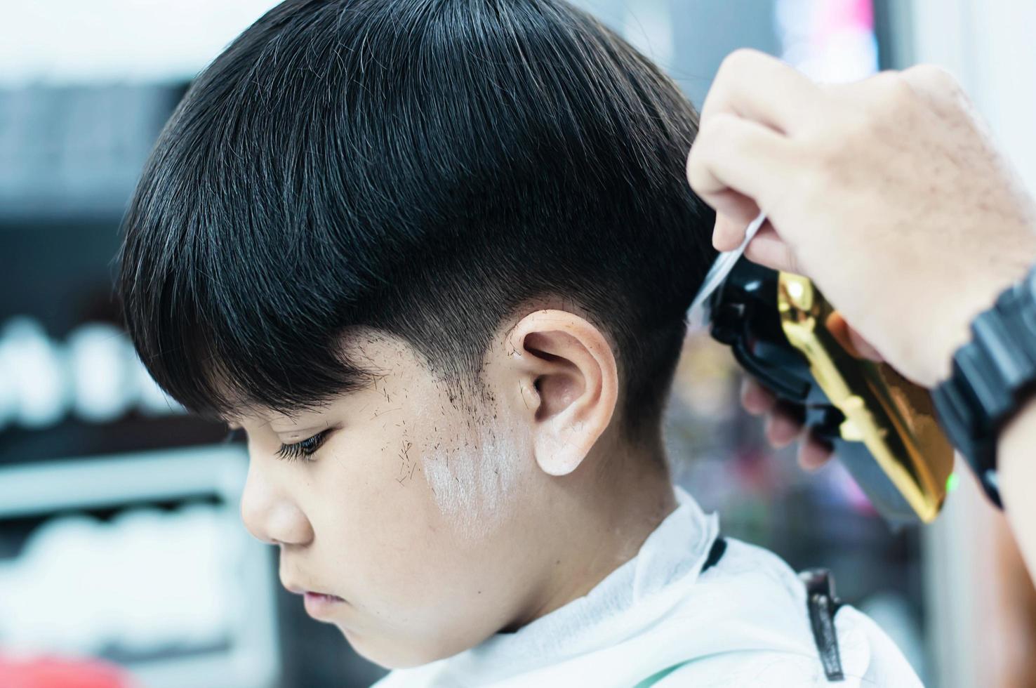 ragazzo asiatico è tagliato i capelli nel negozio di barbiere - persone nel concetto di salone di bellezza parrucchiere foto