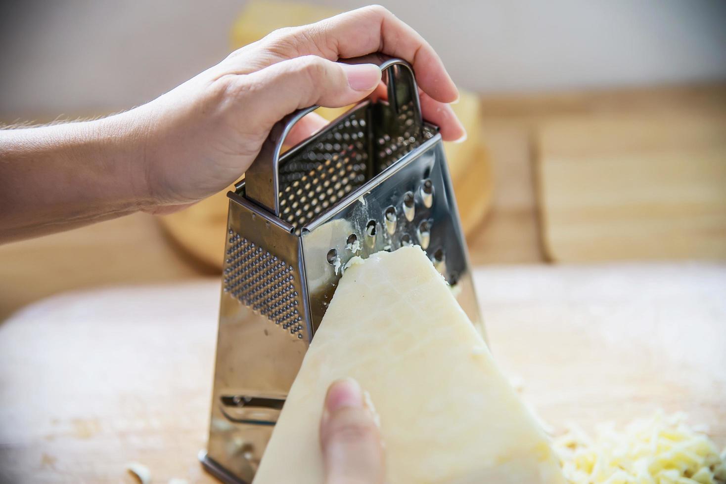 donna che prepara il formaggio per cucinare usando la grattugia in cucina - persone che producono cibo con il concetto di formaggio foto