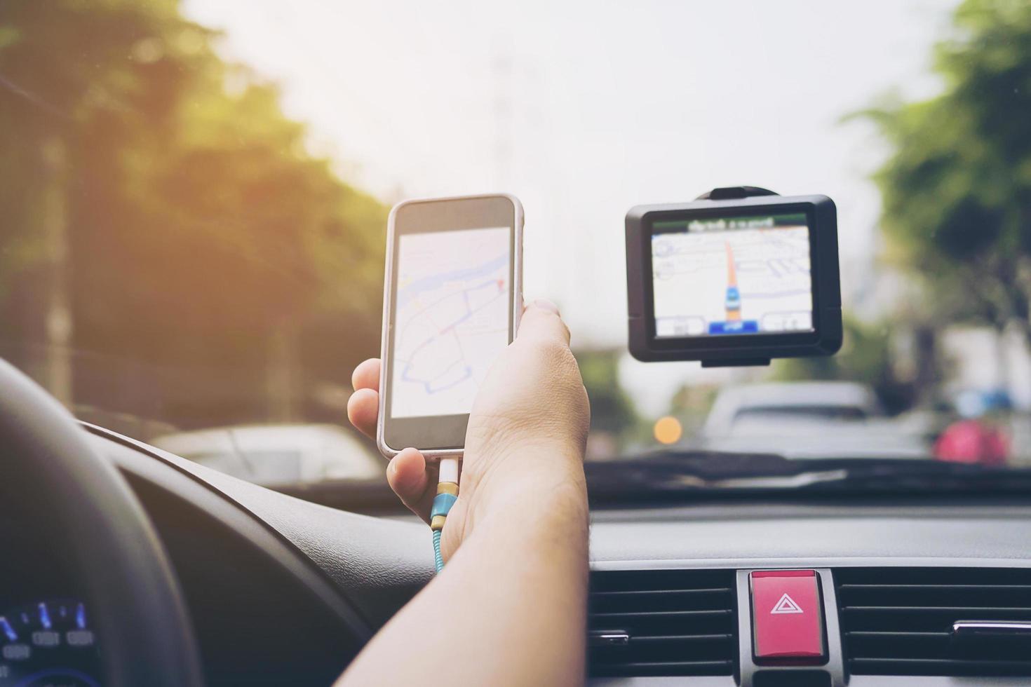 uomo che guida l'auto utilizzando il navigatore e guardando la mappa sul telefono cellulare foto