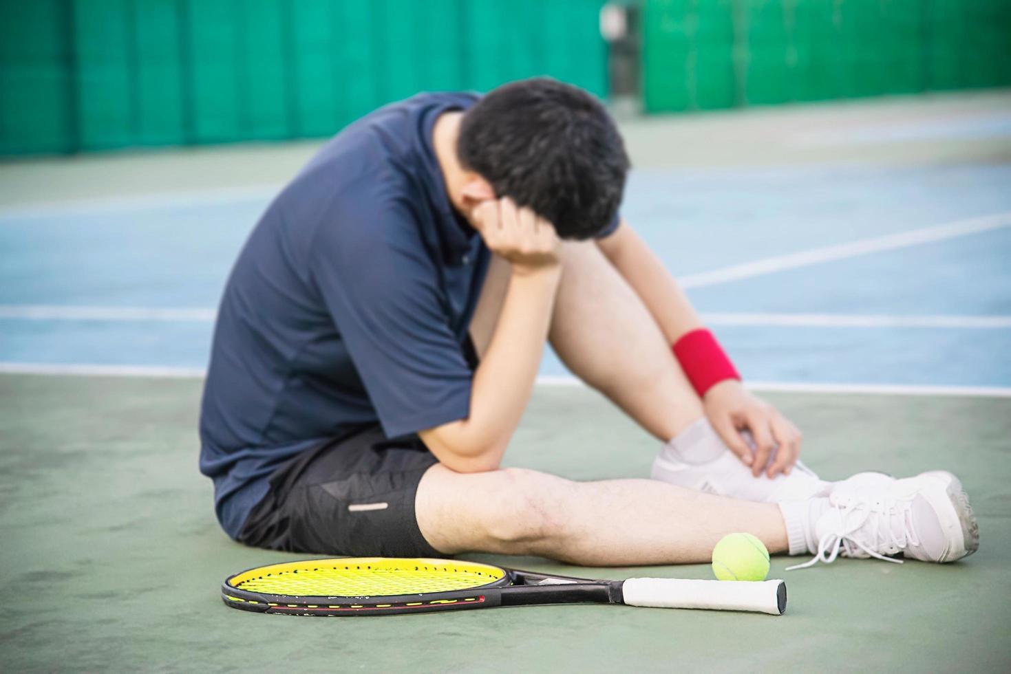 giocatore di tennis triste seduto in tribunale dopo aver perso una partita - persone nel concetto di gioco di tennis sportivo foto