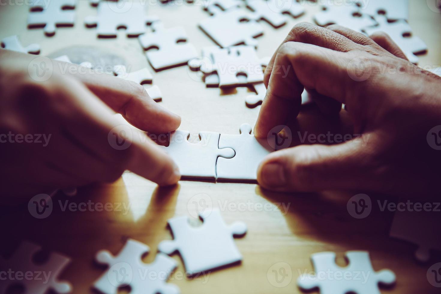 mani di una persona piccolo bambino e genitore che giocano insieme a un puzzle puzzle su un tavolo di legno a casa, concetto per il tempo libero con la famiglia, giocare con lo sviluppo, l'istruzione e il divertimento dei bambini. foto