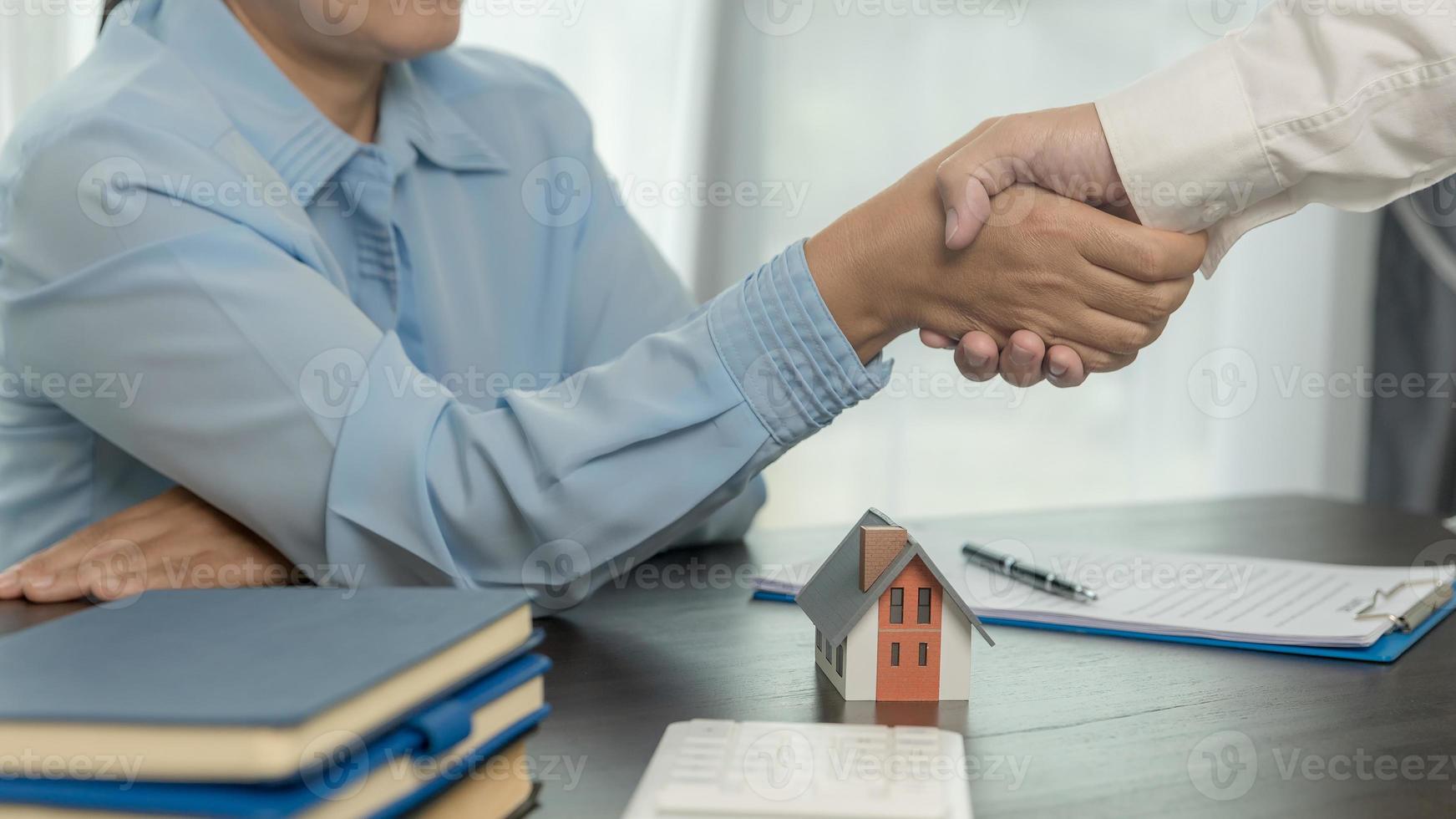 agente immobiliare che stringe la mano al cliente dopo la firma del contratto e l'affare concluso per il trasferimento del diritto di proprietà. uomo broker agente immobiliare agente immobiliare stringere la mano a clienti felici proprietari di case foto