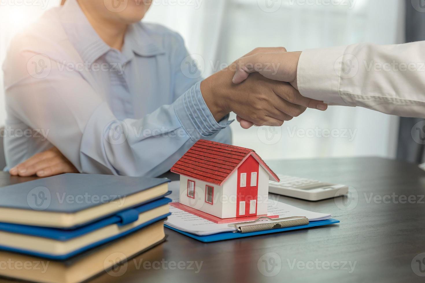 agente immobiliare che stringe la mano al cliente dopo la firma del contratto e l'affare concluso per il trasferimento del diritto di proprietà. uomo broker agente immobiliare agente immobiliare stringere la mano a clienti felici proprietari di case foto