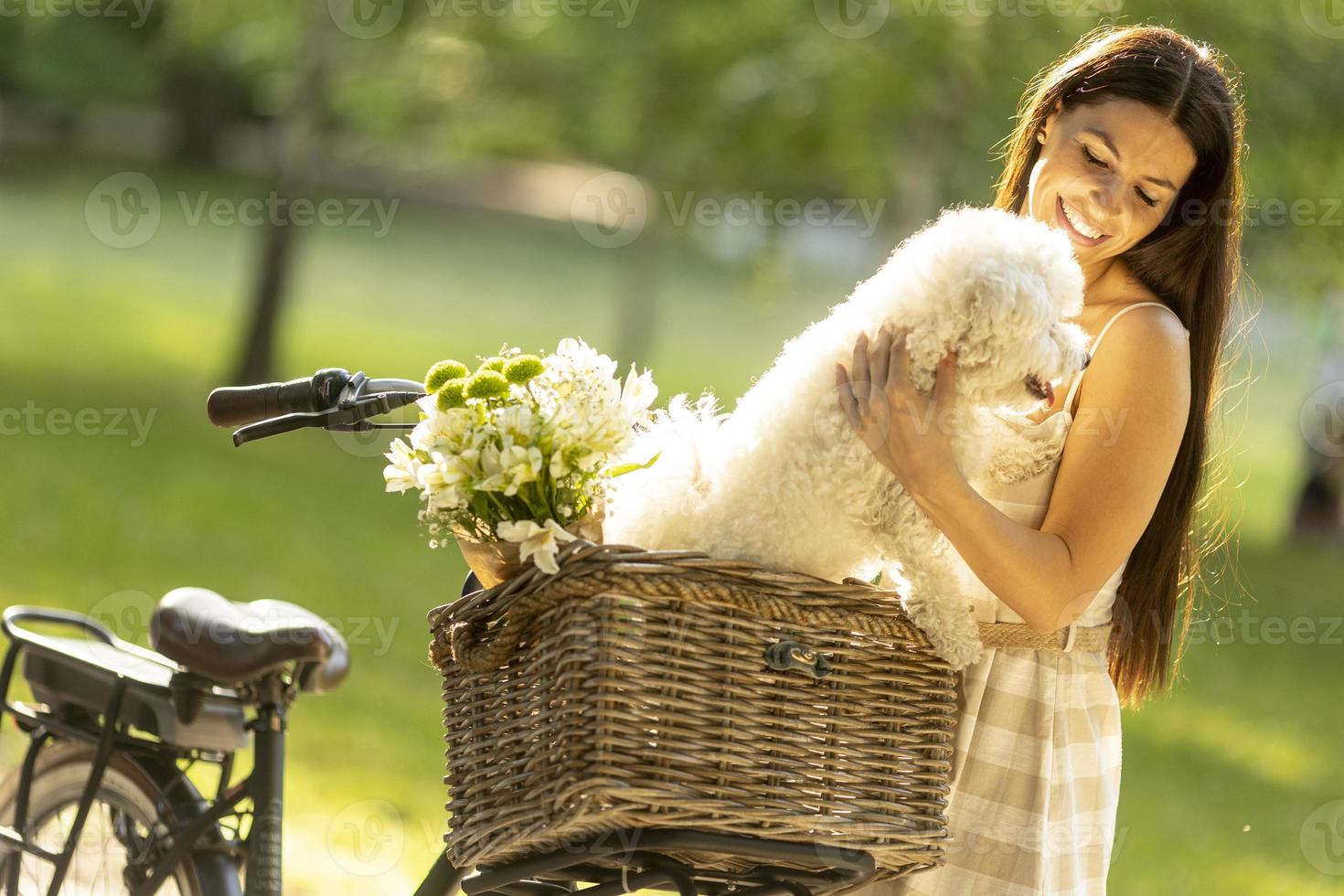 giovane donna con cane bianco bichon frise nel cestino della bici elettrica foto