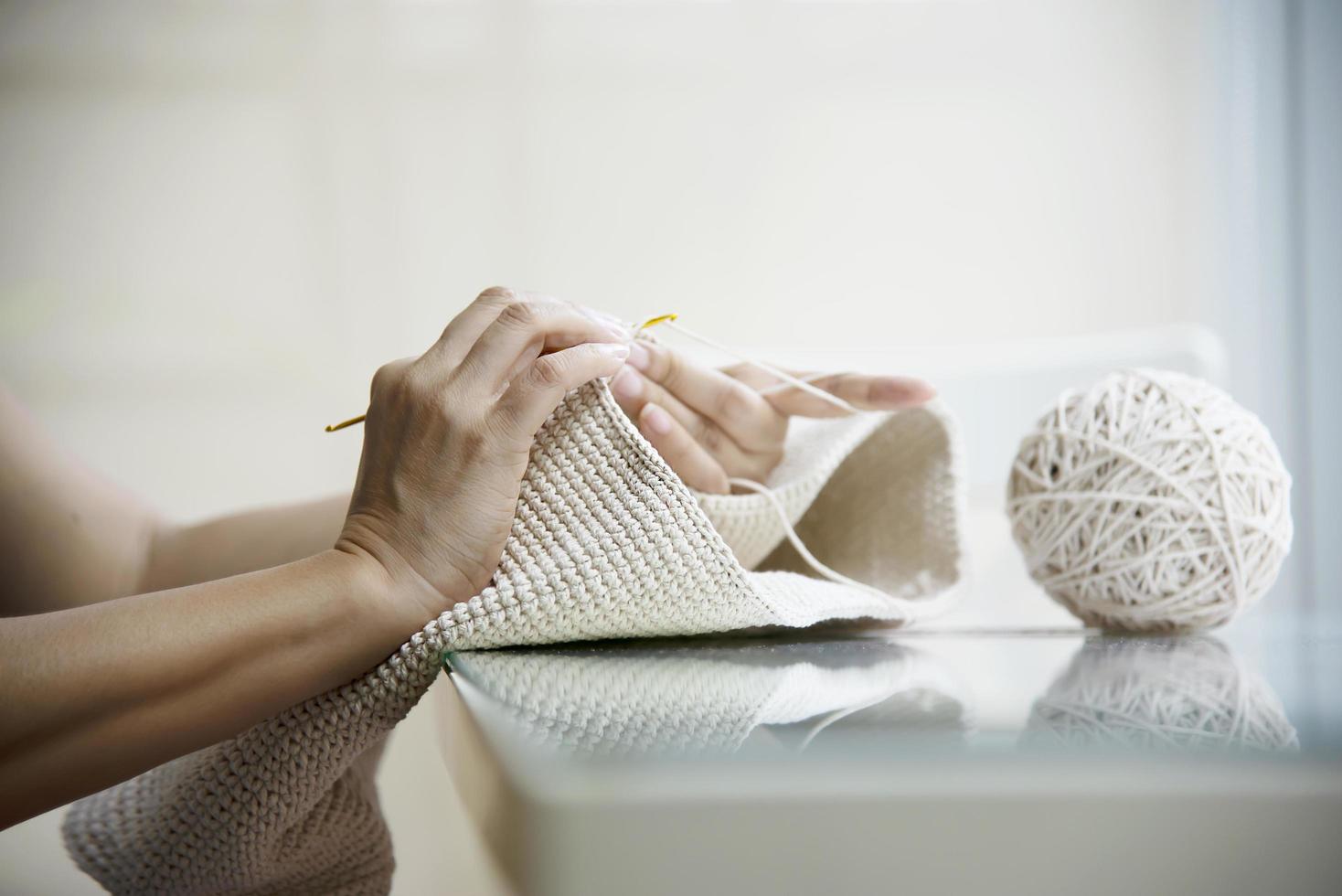 le mani della donna che fanno il lavoro a maglia a casa - le persone con il lavoro fai da te a casa concetto foto