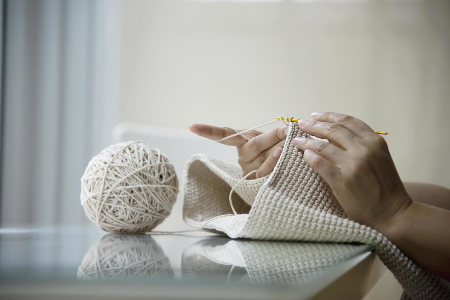 le mani della donna che fanno il lavoro a maglia a casa - le persone con il lavoro fai da te a casa concetto foto