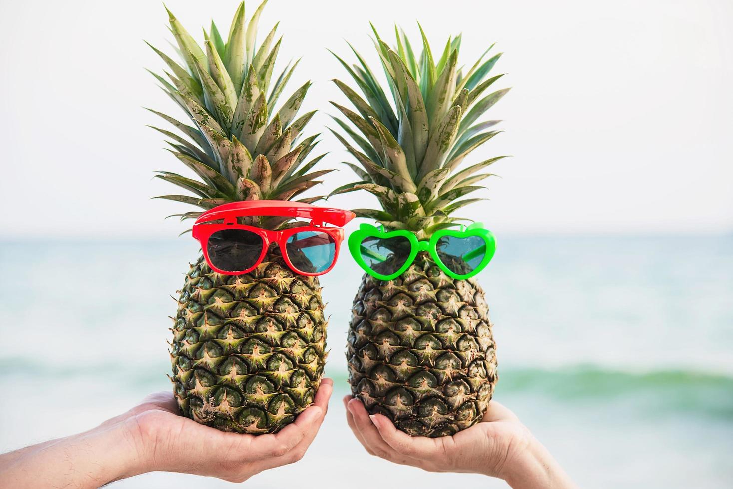 bella coppia fresca ananas mettendo gli occhiali nelle mani dei turisti con sfondo onda del mare - amore felice e divertimento con un sano concetto di vacanza foto