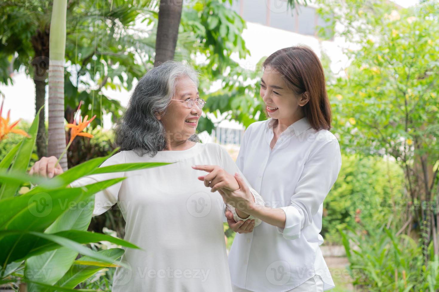 un'anziana anziana donna asiatica e cammina nel cortile con sua figlia. concetto di felice pensionamento con la cura di un caregiver e risparmi e assicurazione sanitaria senior, famiglia felice foto