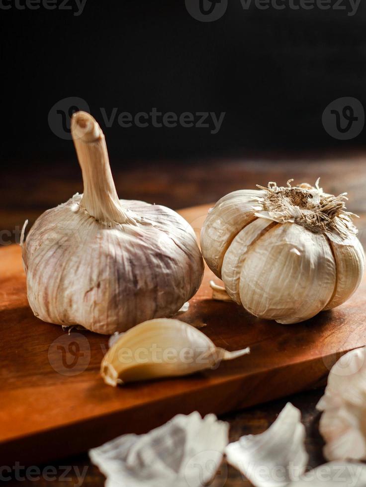 aglio fresco sul piatto di legno sfondo scuro foto