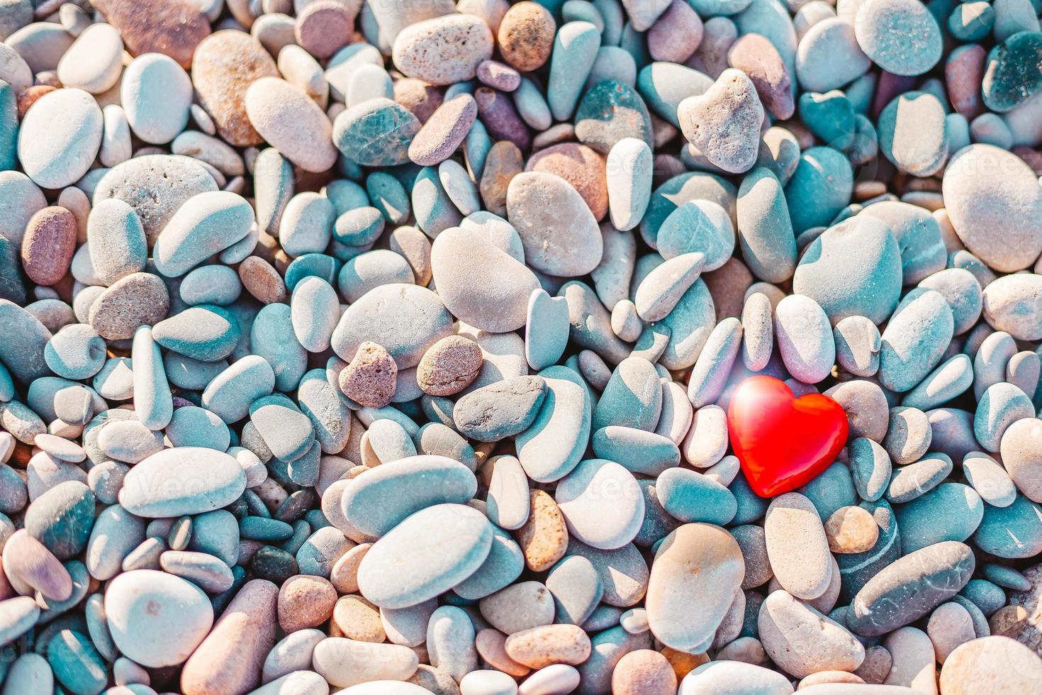 simbolo romantico del cuore rosso sulla spiaggia di ciottoli foto