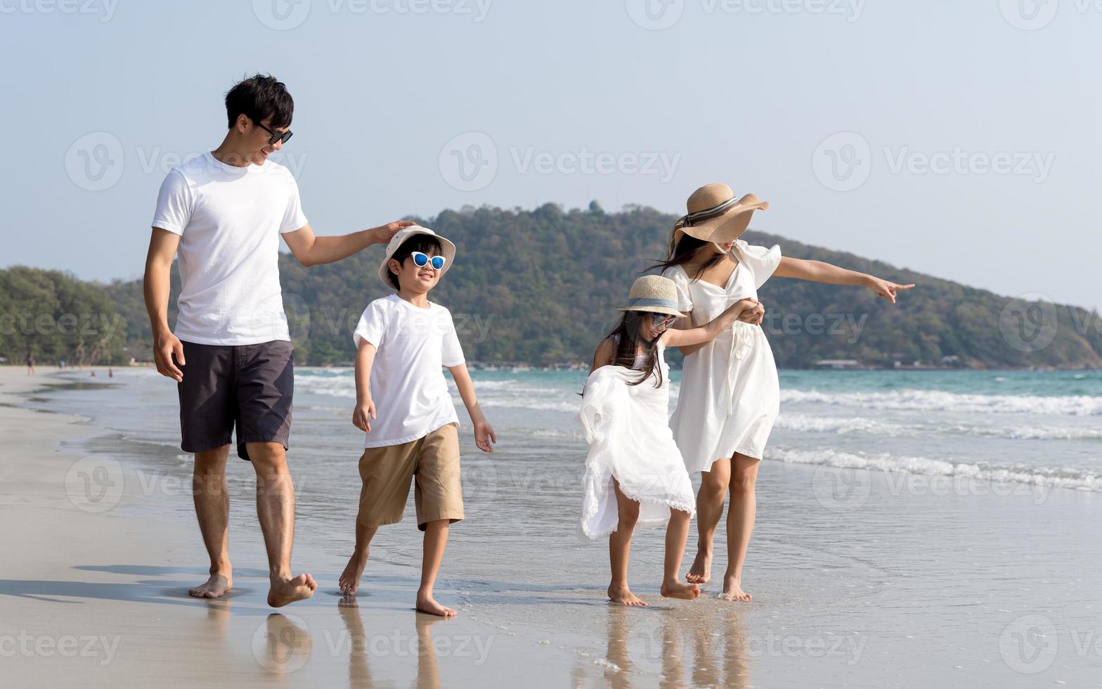 famiglia asiatica che cammina in spiaggia con il concetto di vacanza felice dei bambini foto