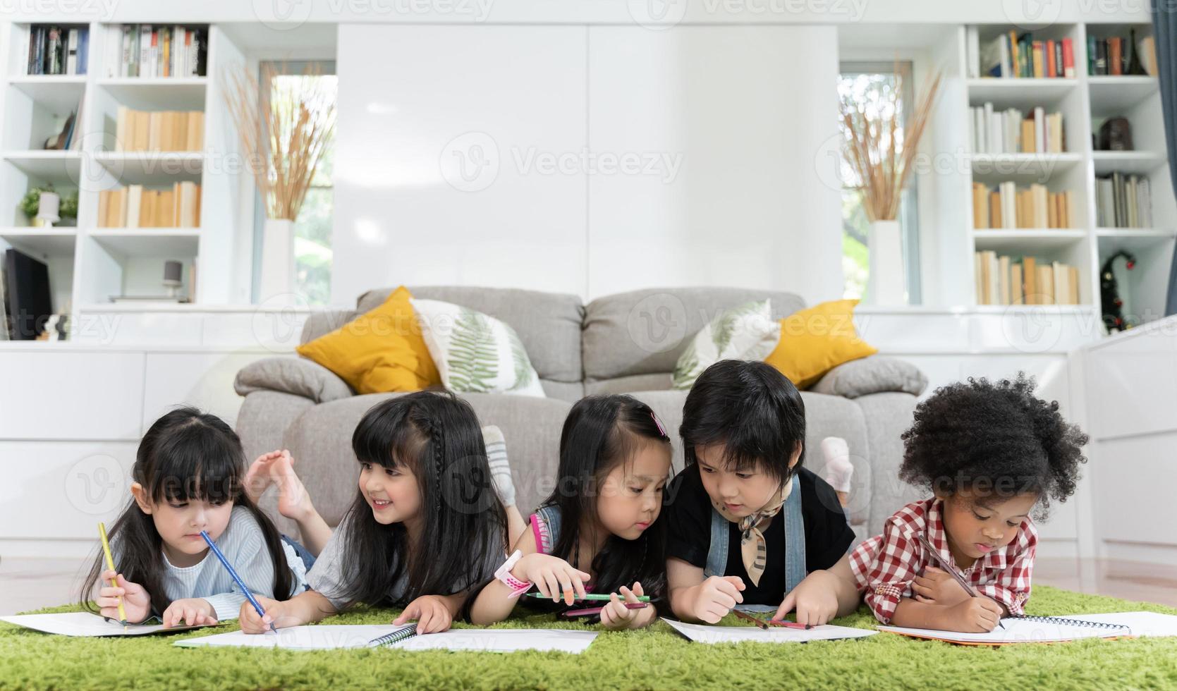 gruppo di bambini in età prescolare che disegnano carta con matite colorate foto