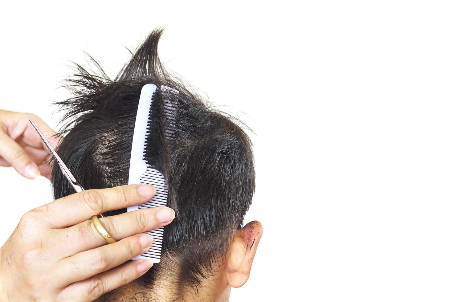 un ragazzo è tagliato i capelli dal parrucchiere isolato su sfondo bianco foto