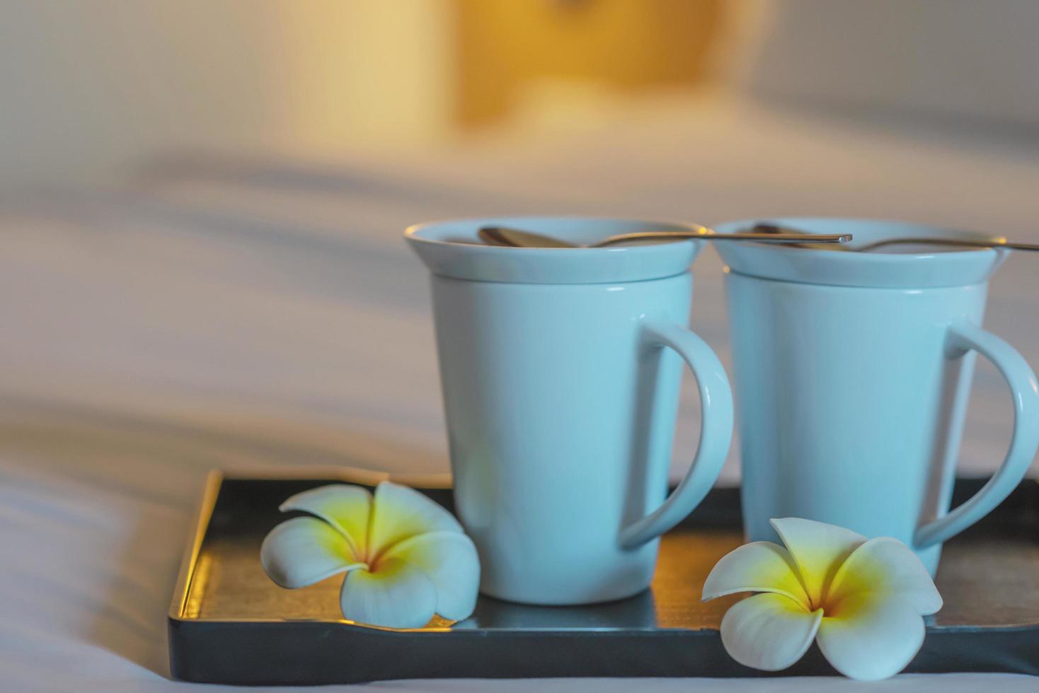 primo piano della tazza di caffè di benvenuto doppia sul letto bianco nella camera d'albergo - concetto di viaggio di vacanza di ospitalità dell'hotel foto