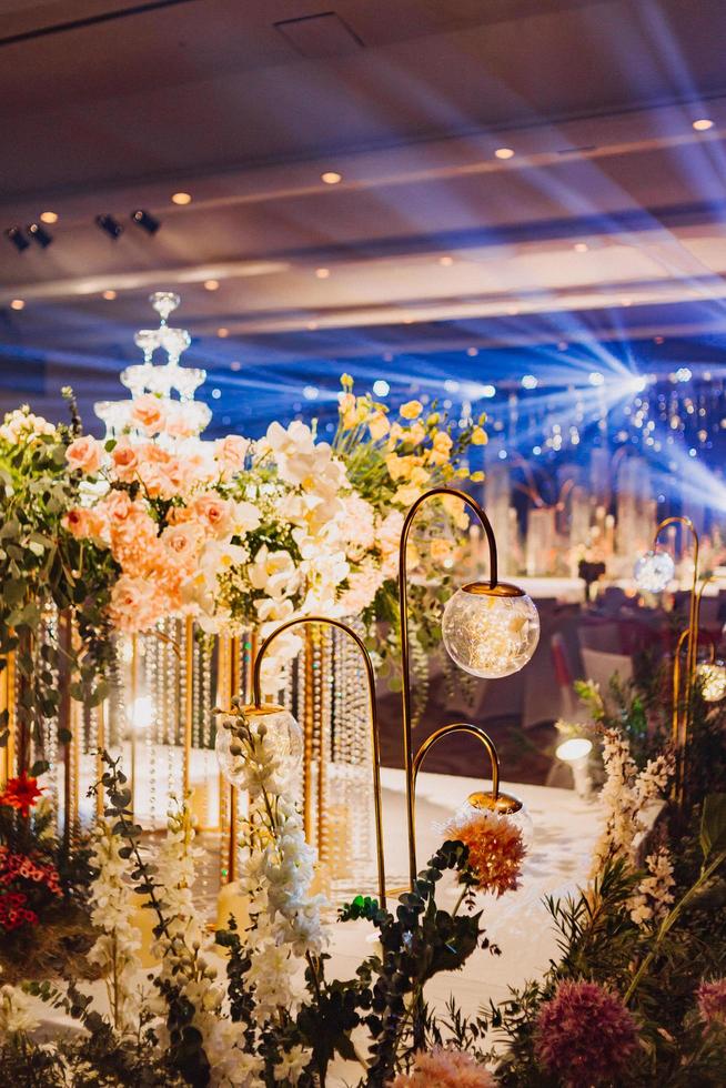 composizione floreale per il matrimonio estivo, fatta di rose e rami verdi su un tavolo da pranzo nel ristorante. , bicchieri e piatti nel ristorante all'aperto in una giornata ventosa con effetto grana della pellicola foto