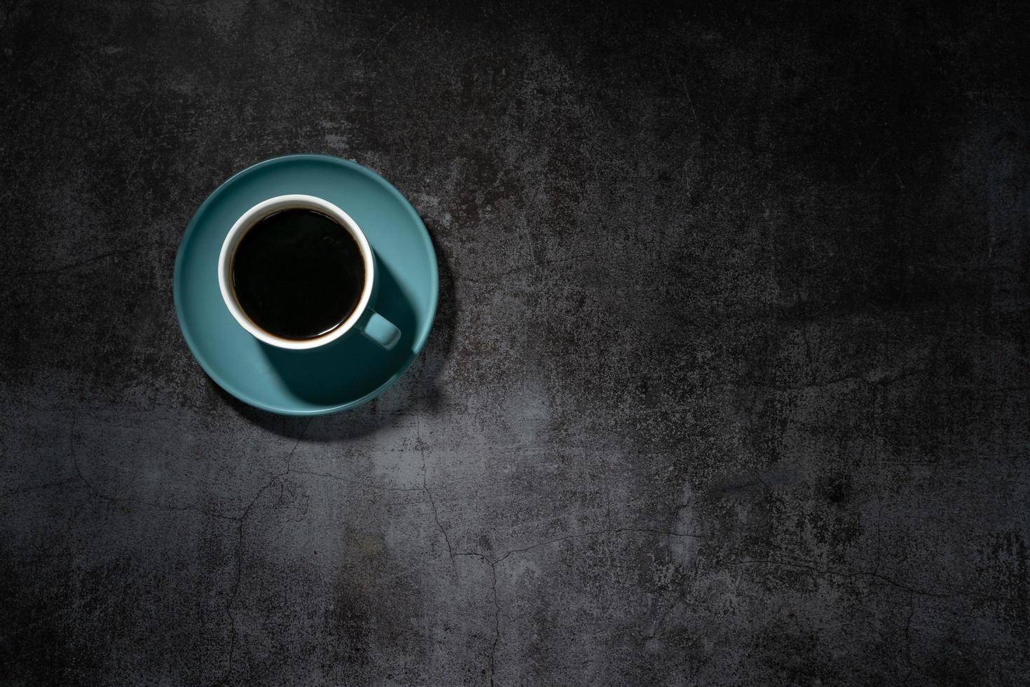caffè nero in una tazza di ceramica blu sul vecchio pavimento di cemento grigio foto