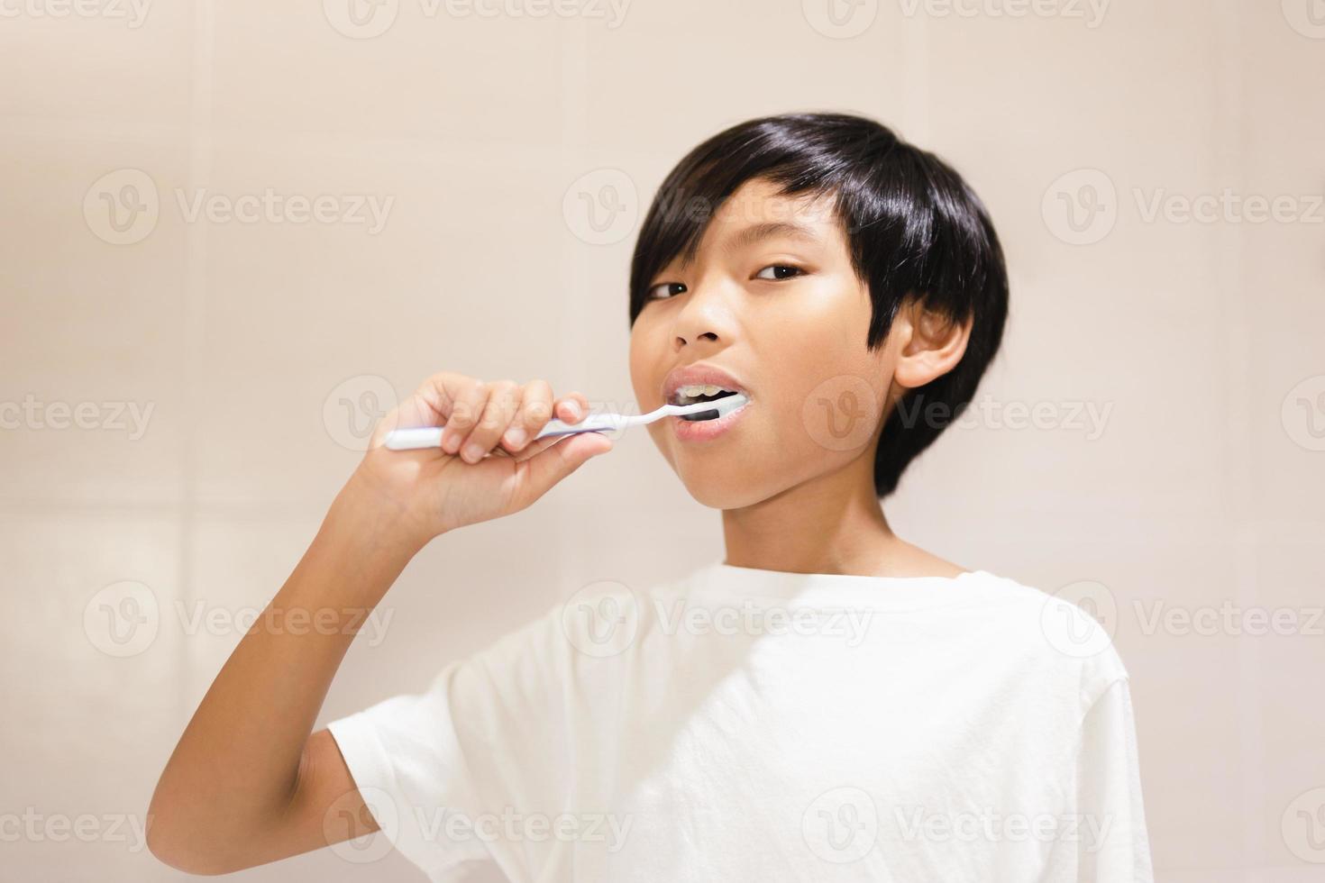 ragazzo che si lava i denti con lo spazzolino da denti in bagno. foto