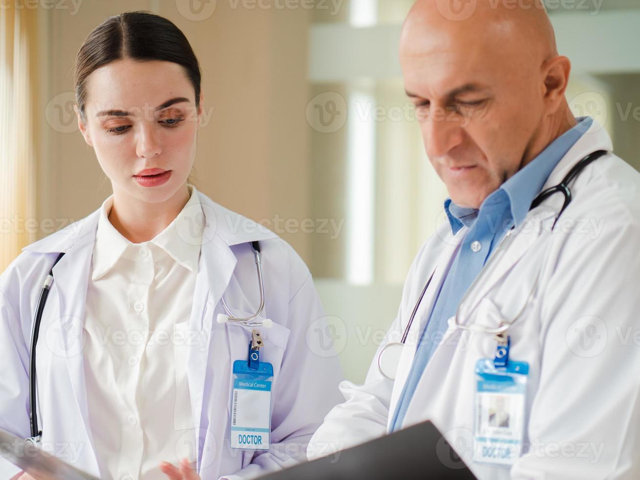 il fuoco selettivo alla dottoressa si concentra sulla consulenza, discutendo con il collega maschio in ospedale. due specialisti sanitari professionisti in piedi in clinica mentre fanno brainstorming come lavoro di squadra medica. foto