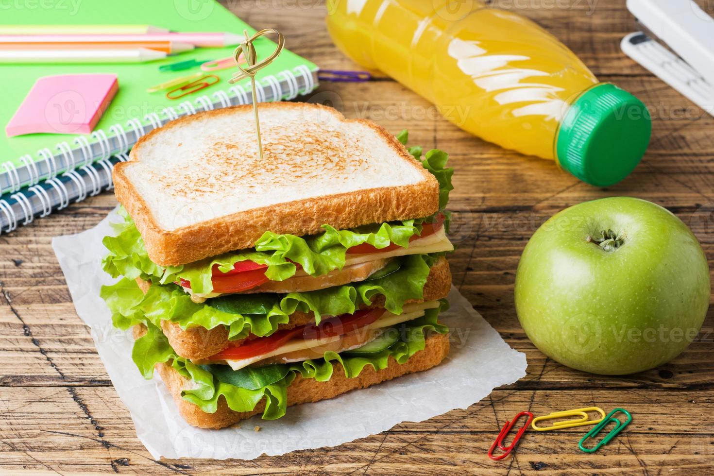 pranzo salutare per la scuola con panino, mela fresca e succo d'arancia. forniture scolastiche colorate assortite. copia spazio. foto